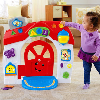 Toddler reaching up to a red and white Fisher-Price activity house play set