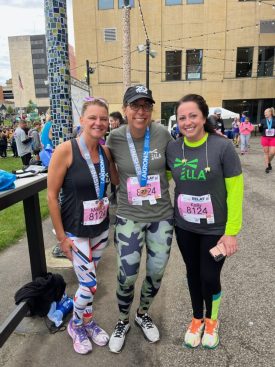 Three LLA Therapy team members wearing race bibs and medals outdoors after a race