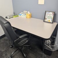 Therapy room with a desk, rolling chair and framed art on the wall