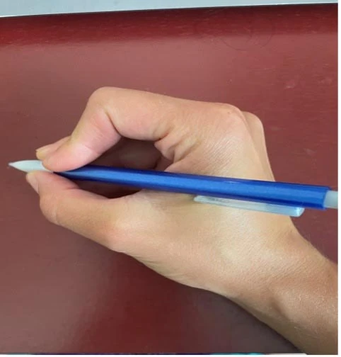 Hand holding a blue pencil in a grasp for writing