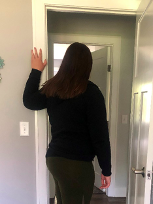 Woman standing in a doorway with her arm raised against the door frame to demonstrate a pectoralis stretch